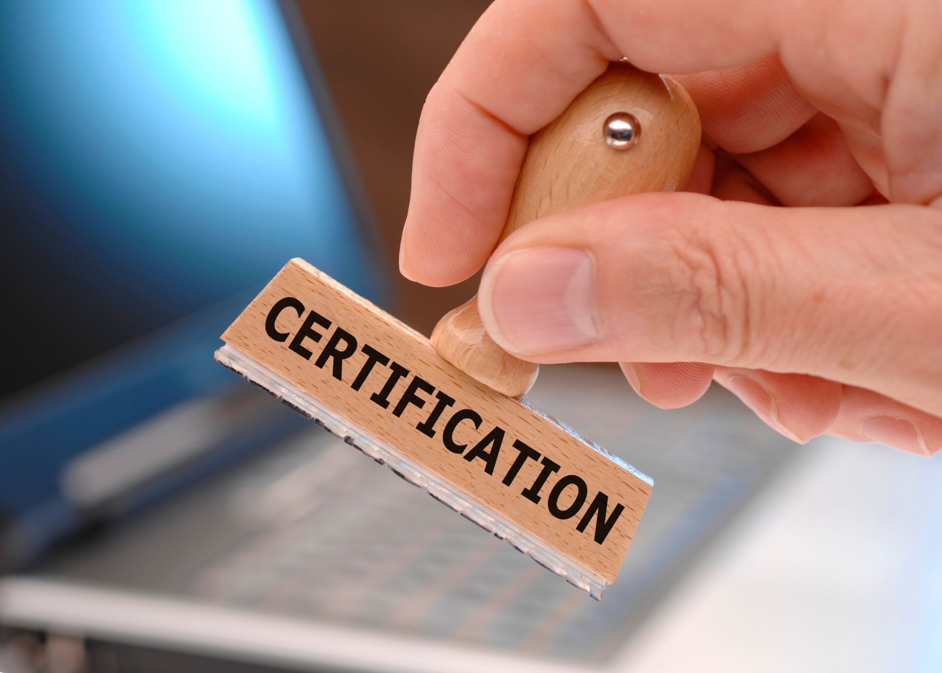 Certification stamp help in male hand with computer in background